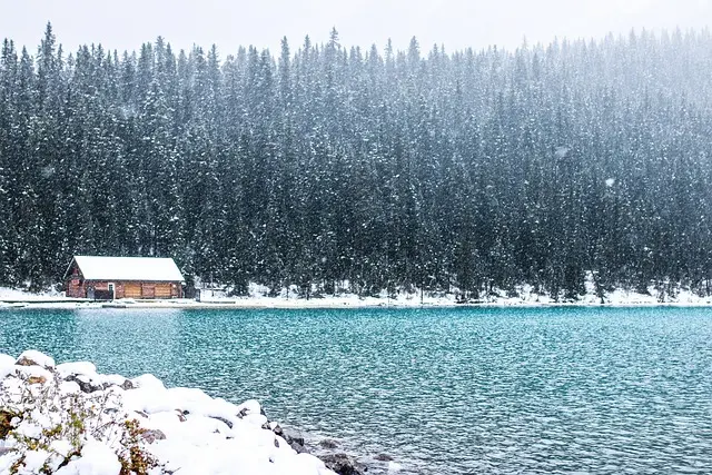 A cabin sitting on the shore of lake louise pictured in front of the rockies.